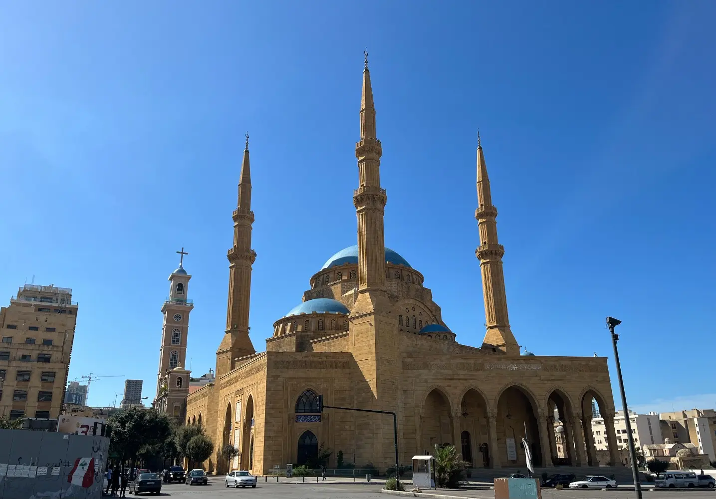 Bal rengi ile kum rengi arası bir tonda cami görünüyor, mavi kubbesi gökyüzü mavisine yakın bir renkte turkuaz tonunda.