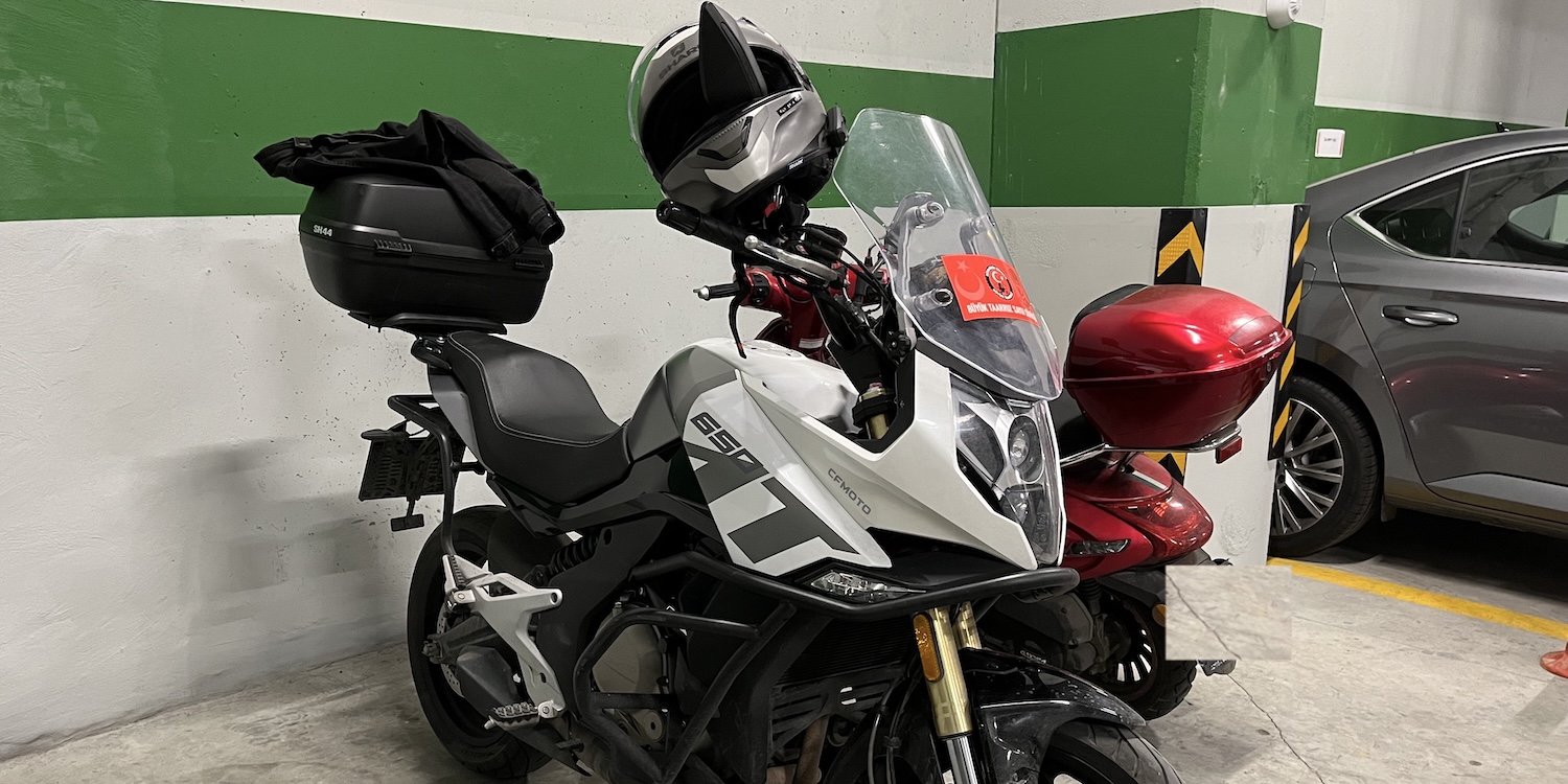Türkçe: motosikletimin sağ ön tarafından göz hizasından çekilmiş bir fotoğrafı; sağ aynası üzerinde kaskım yukarı bakacak şekilde takılı.